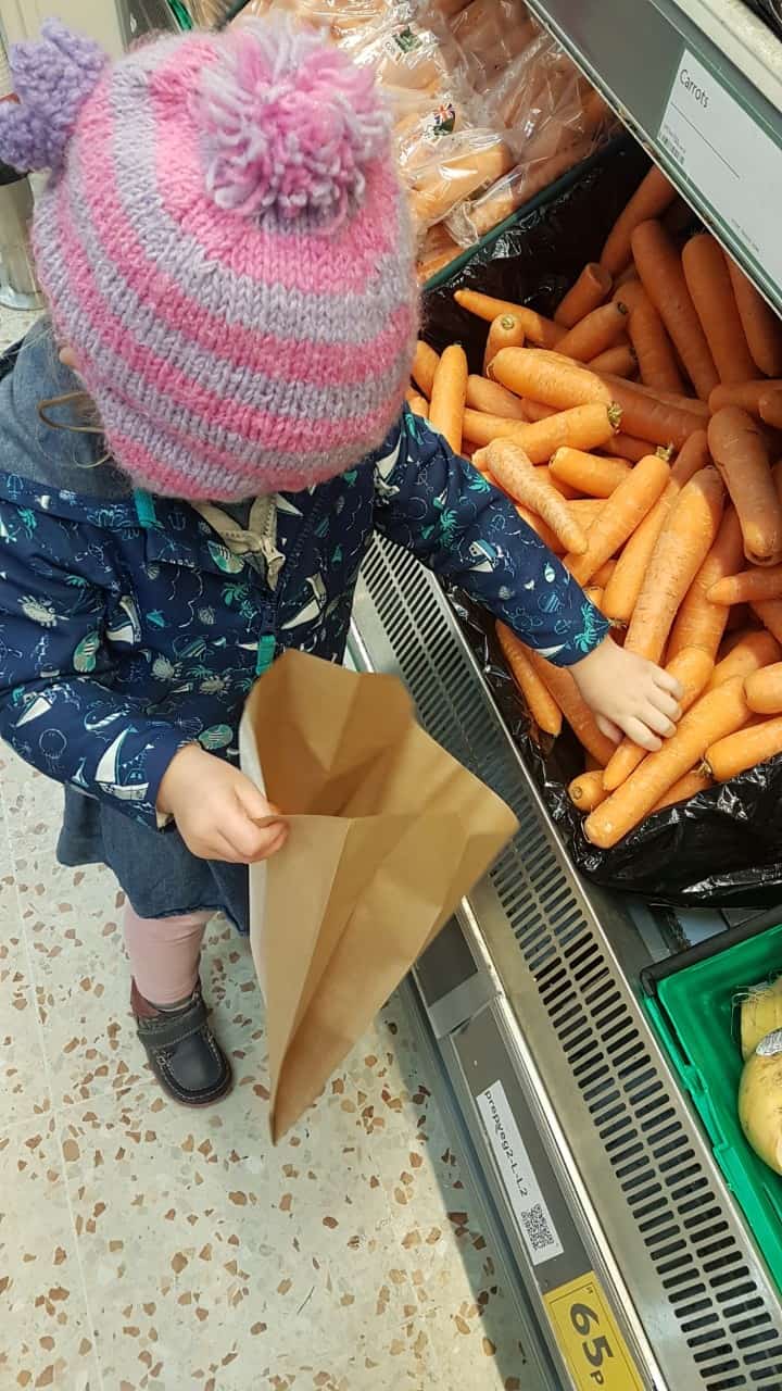 FCSS - young child bagging carrots in a supermarket