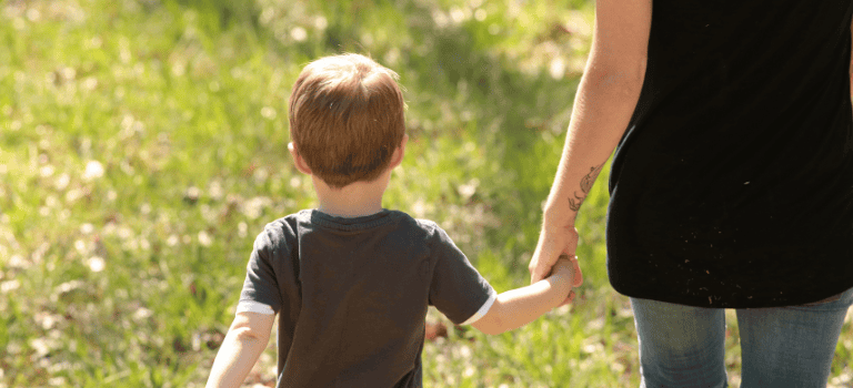 FCSS child holding hands with his mum in a field